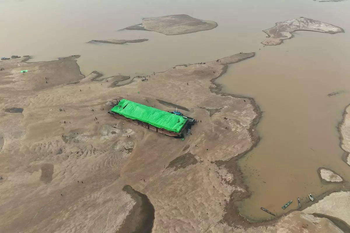 People surround a barge that is stranded on a dry riverbed of the Kapuas River amid a drought in Sekadau, West Kalimantan, Indonesia, Friday, Sept. 11, 2026. (AP Photo/Tatan Syuflana)