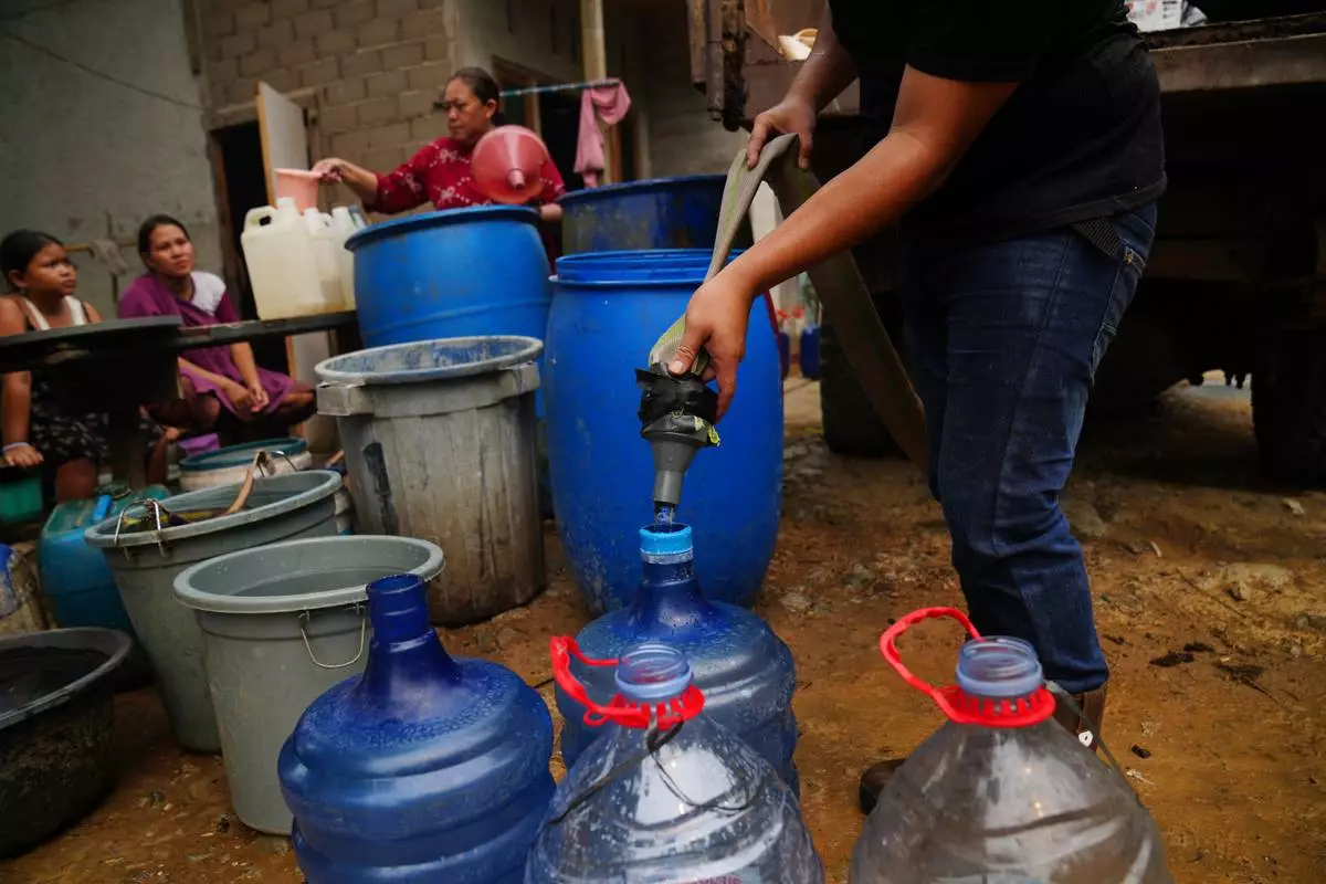 A resident fills their container with clean water as others wait for their turn from a tanker truck amid a drought in Sanggau, West Kalimantan, Indonesia, Friday, Sept. 11, 2026. (AP Photo/Tatan Syuflana)