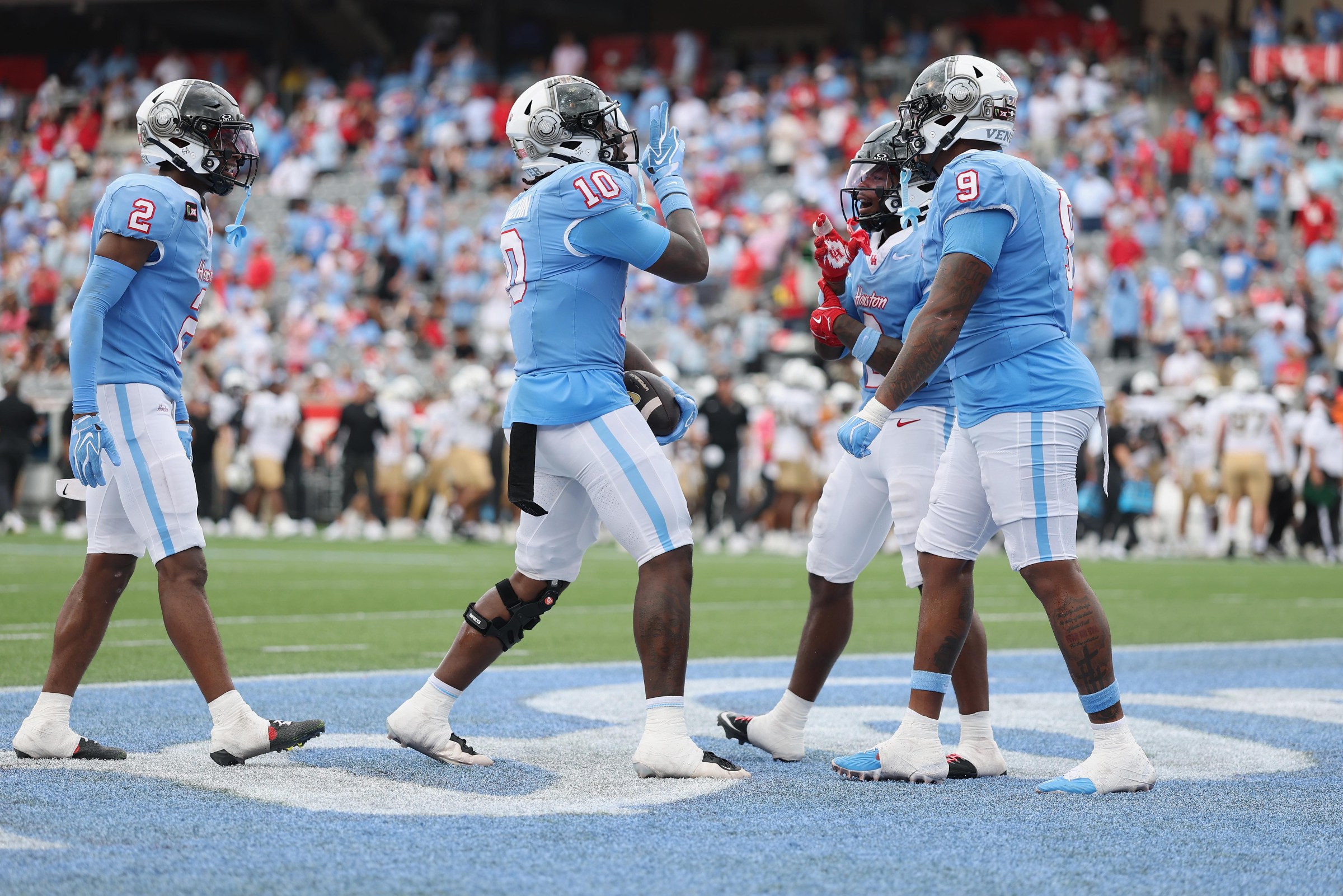 HOUSTON, TEXAS - OCTOBER 03: Latreveon McCutchin #10 of the Houston Cougars is congratulated by Javion White #0 and Ashton Porter #9 after a turnover in the second half against the UCF Knights at TDECU Stadium on October 03, 2026 in Houston, Texas. (Photo by Tim Warner/Getty Images)