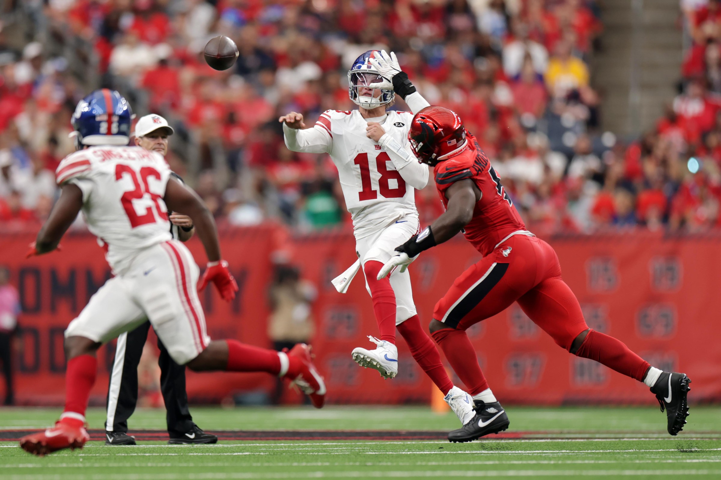 HOUSTON, TEXAS - OCTOBER 25: J.J. McCarthy #18 of the New York Giants throws a pass while being pressured by Will Anderson Jr. #51 of the Houston Texans during the fourth quarter at NRG Stadium on October 25, 2026 in Houston, Texas. (Photo by Kenneth Richmond/Getty Images)