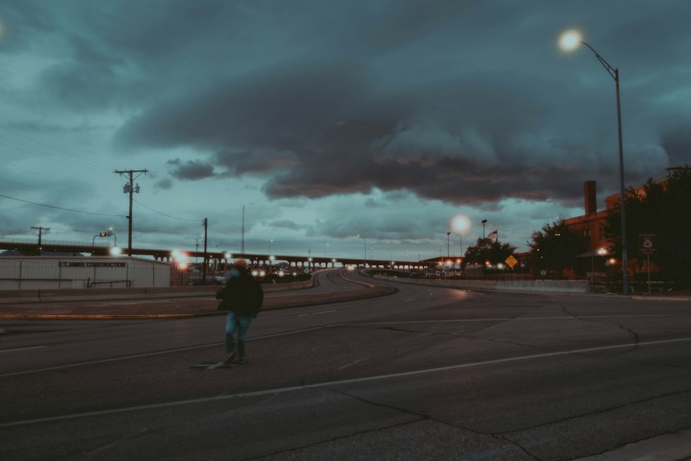 silhouette of person walking on sidewalk during night time