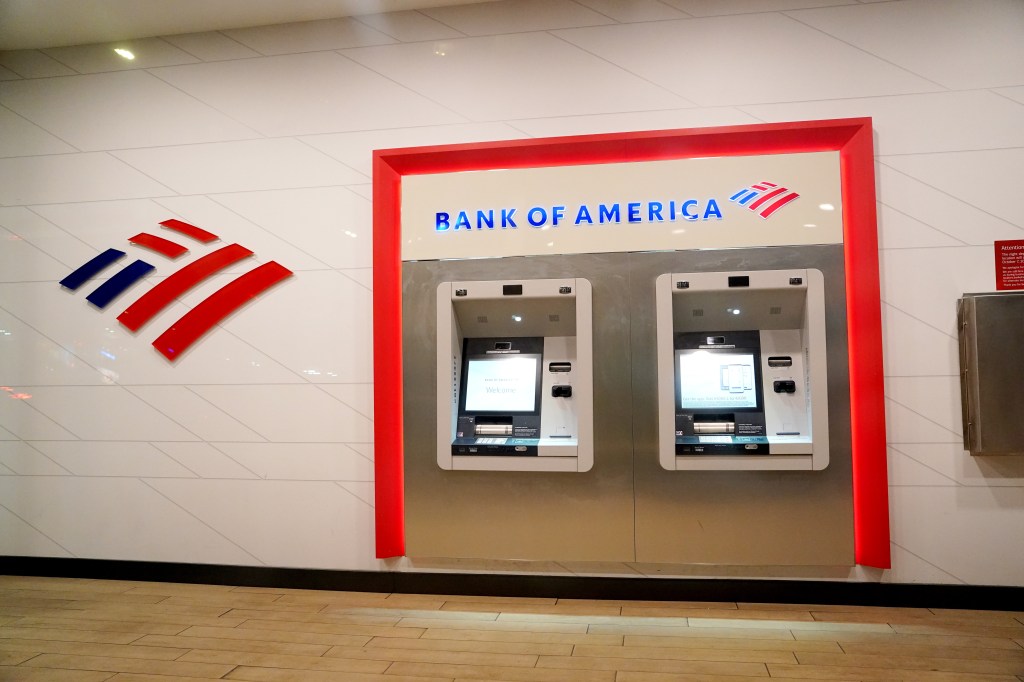 Bank of America ATMs built into a wall beneath a large bank logo.