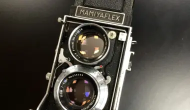 Vintage Mamiyaflex twin-lens reflex camera with a black body, chrome lens barrels, and waist-level viewfinder hood, resting on a dark surface.