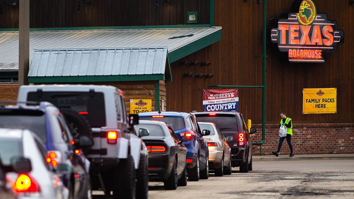 Cars line up for the drive-thru during the dinner service at Texas Roadhouse, Friday, March 27, 2020, in Springfield, Ill. The restrictions have closed dinning rooms for area restaurants because of the COVID-19 pandemic, but restaurants have adapted to serving their customers through to-go services. Customers can order online or through a mobile app as well as onsite ordering when they pull up. 