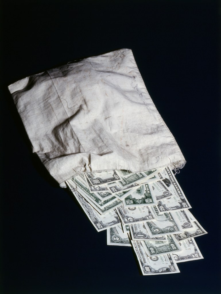 U.S. currency spilling from a cloth bag.