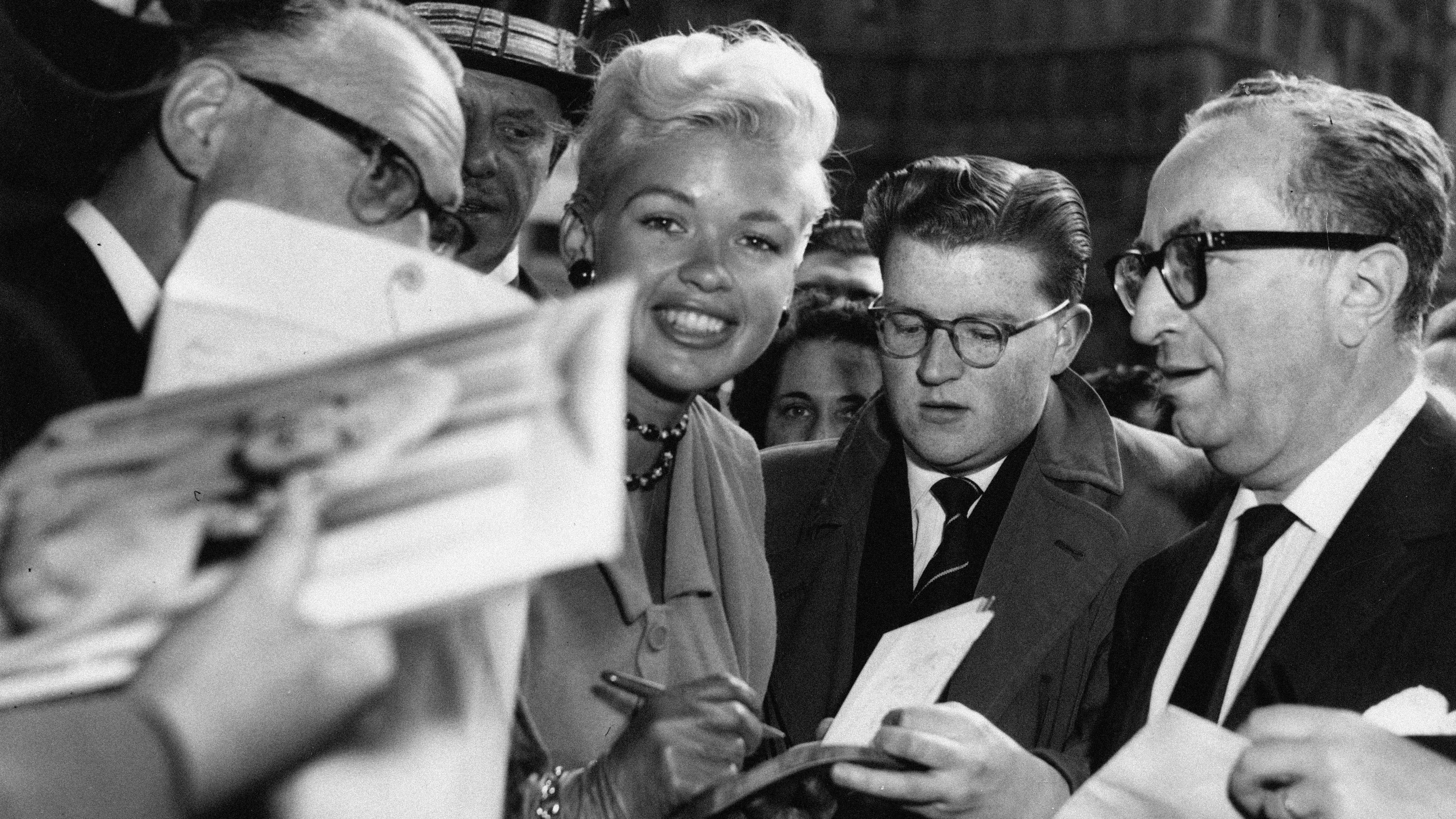 September 25, 1957; London, England, U.K. Jayne Mansfield signing autographs when she arrived at the Dorchester Hotel.