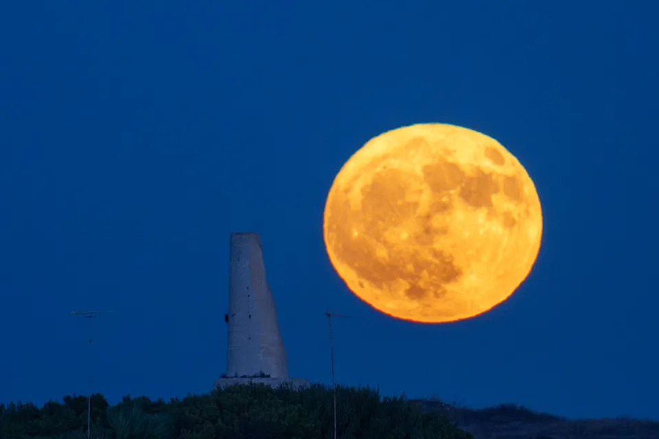 The buck moon rises behind Torre del Serpe in Otranto, Italy. 