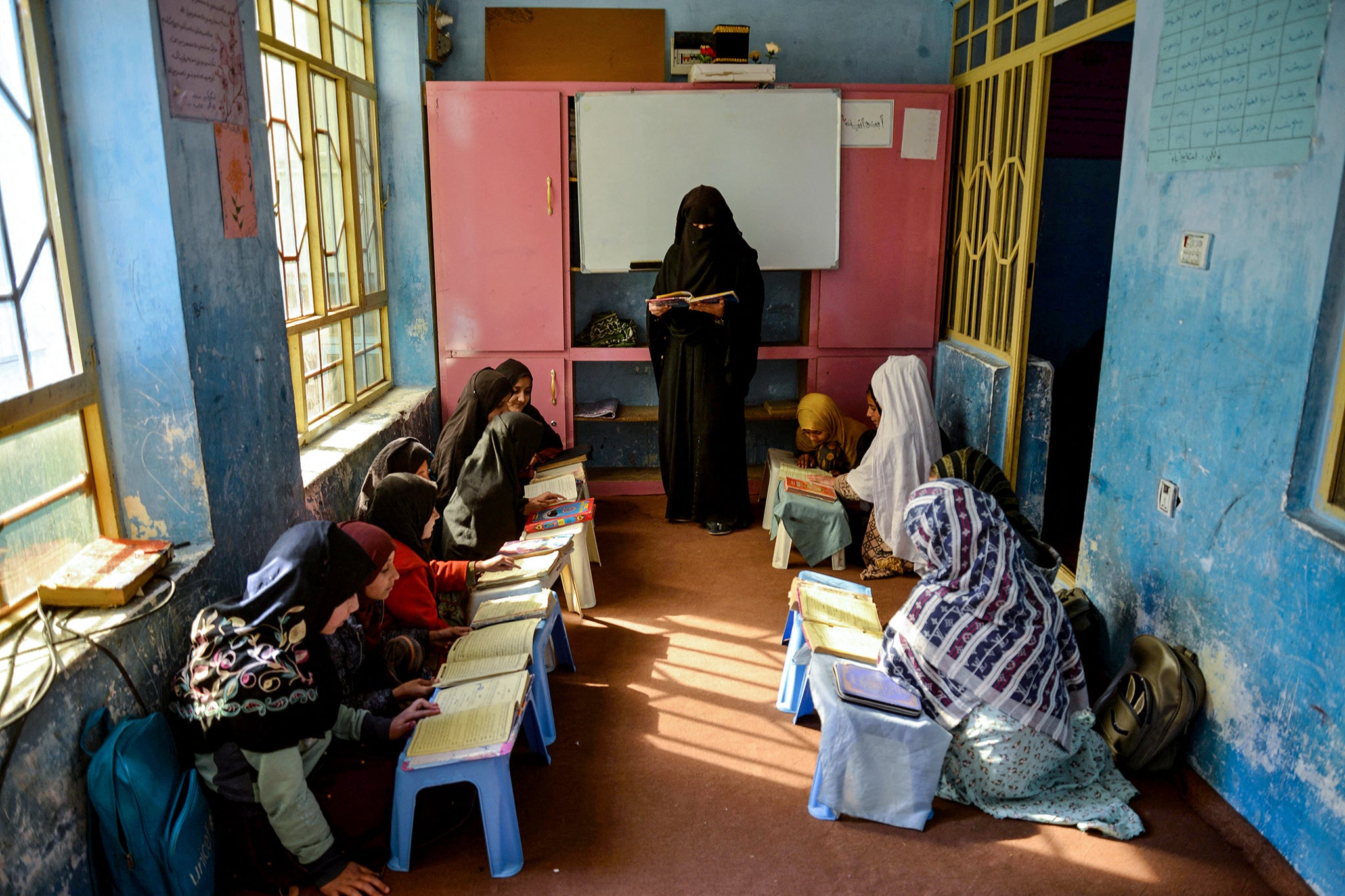 An Afghan woman teaches girls as they read a religious book at a madrassa or Islamic school in Kandahar on March 3, 2025.