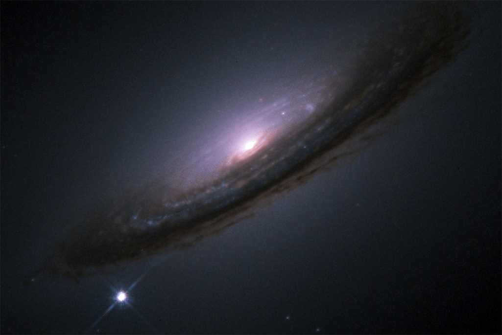 A white dot with diffraction spikes appears near a large swirling galaxy with a bright core.