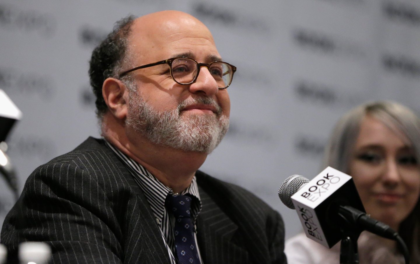 Commentary editor John Podhoretz sits in front of a microphone with “Book Expo” written on it.