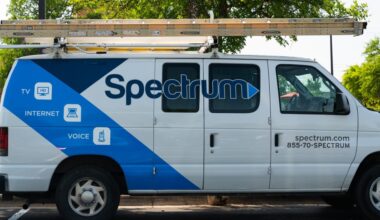 A parked van used by a Spectrum cable technician. The van has the Spectrum logo on its side and a ladder stowed on the roof.
