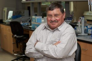Man standing in a lab with his arms crossed