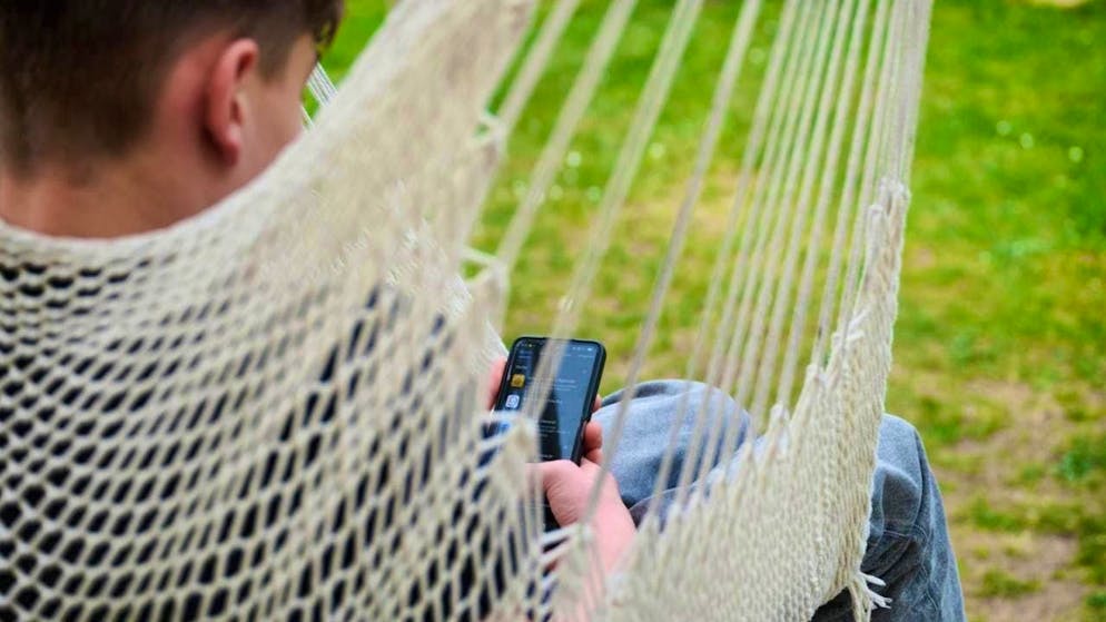 ARCHIVE - A boy looks at his smartphone while sitting in a hanging swing in a garden. Photo: Annette Riedl/dpa/symbol image