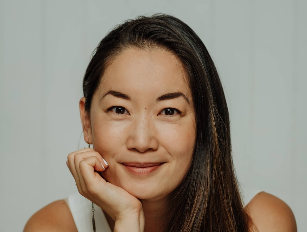 A woman holds her head with her hand and smiles