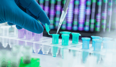 Close up on a scientist's gloved hands pipetting DNA samples into tubes lined up in a row