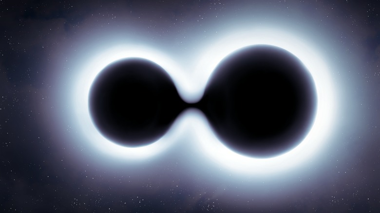 Concept of two black holes merging together into one, light surrounds them