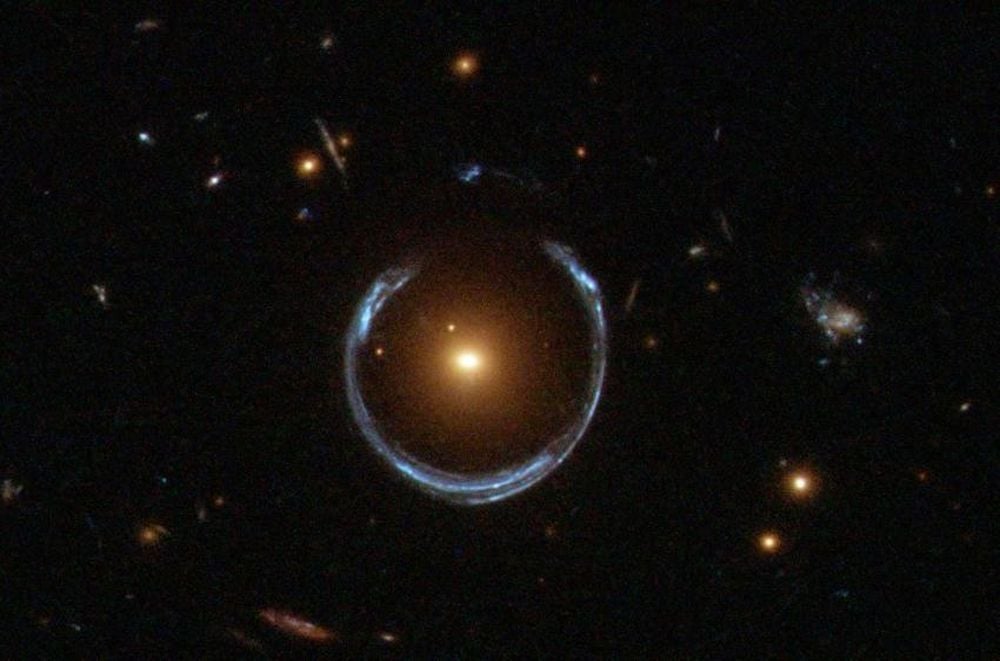 This Hubble Space Telescope image shows the Cosmic Horseshoe gravitational lens. The newly discovered ultramassive blackhole lies at the centre of the orange galaxy. Far behind it is a blue galaxy that is being warped into the horseshoe shaped ring by distortions in spacetime created by the immense mass of the foreground orange galaxy. Image Credit: NASA/ESA. Licence: Attribution (CC BY 4.0)