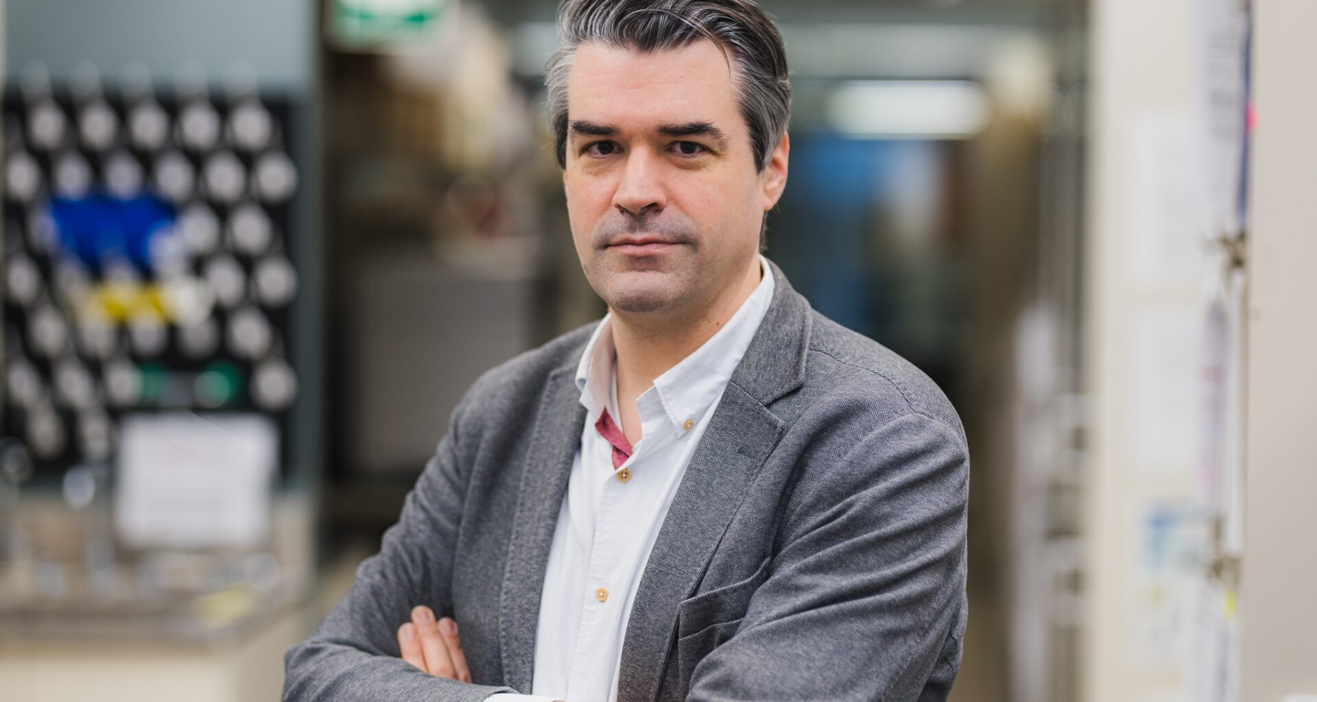 Head and shoulders photo of Dr. Dr. Guillaume Paré, with his arms crossed, smiling with his lab in the background.