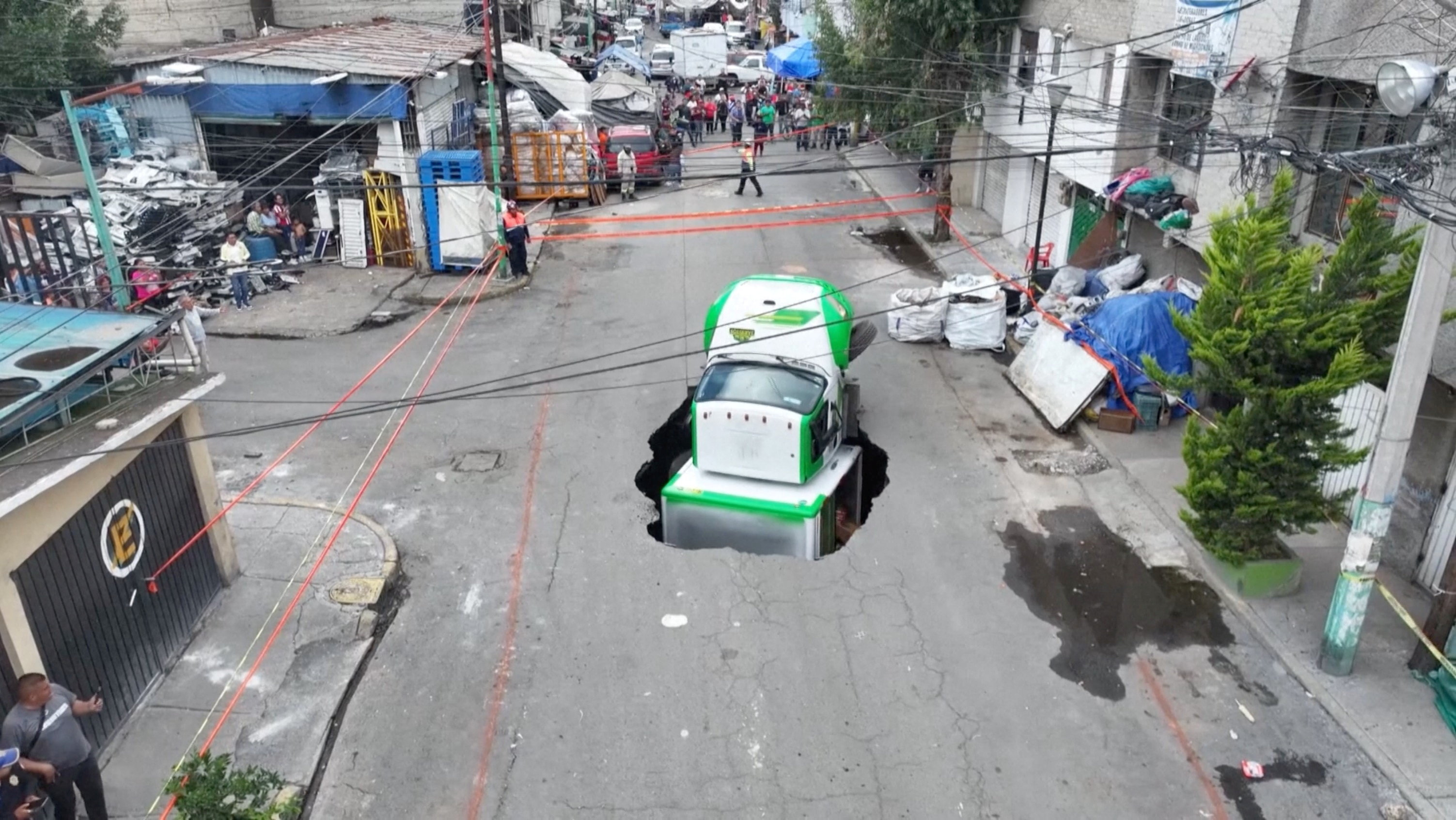 A drone view shows a soda delivery truck collapsing into a sinkhole in Mexico City