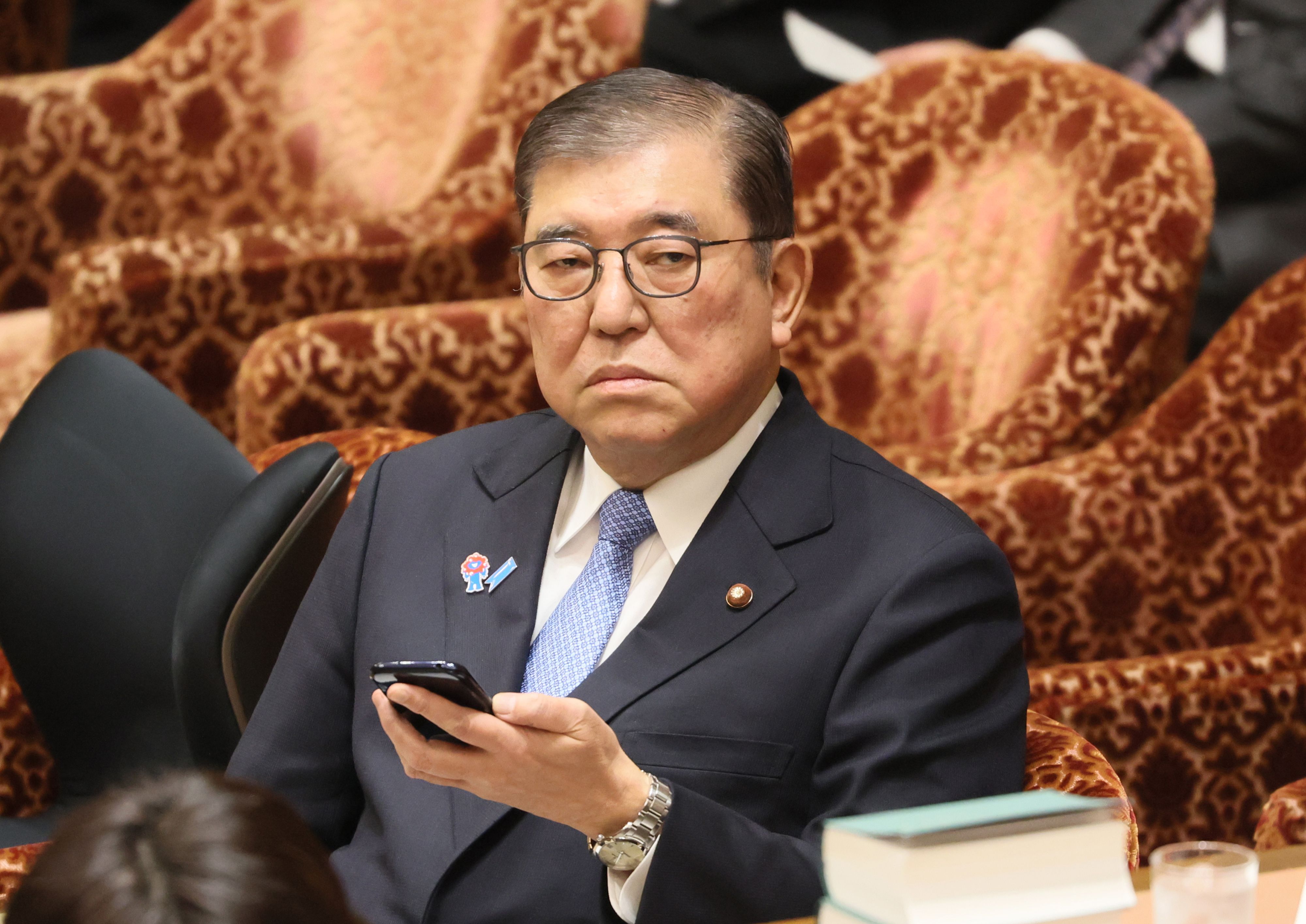 Japanese Prime Minister Shigeru Ishiba using a smartphone at a budget committee session.