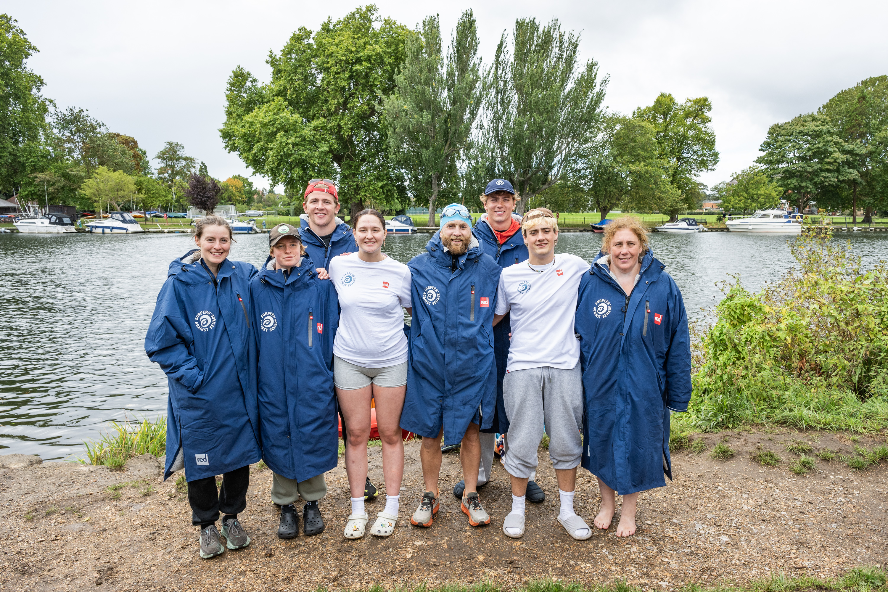 Eight swimmers posing for a photo by a river, advocating for action against sewage pollution.