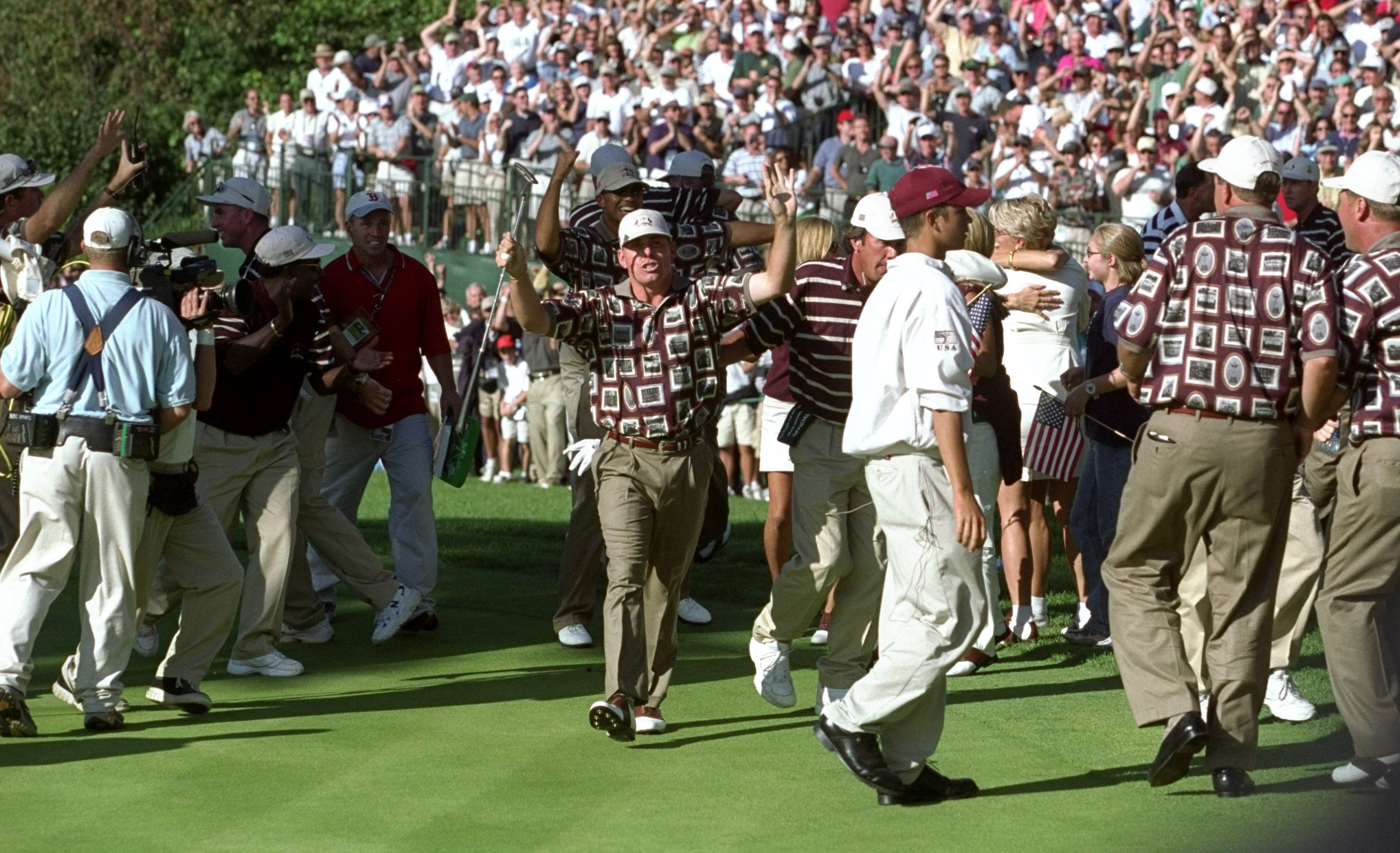 Justin Leonard of the USA navigating through celebrating teammates after a birdie putt at the Ryder Cup.