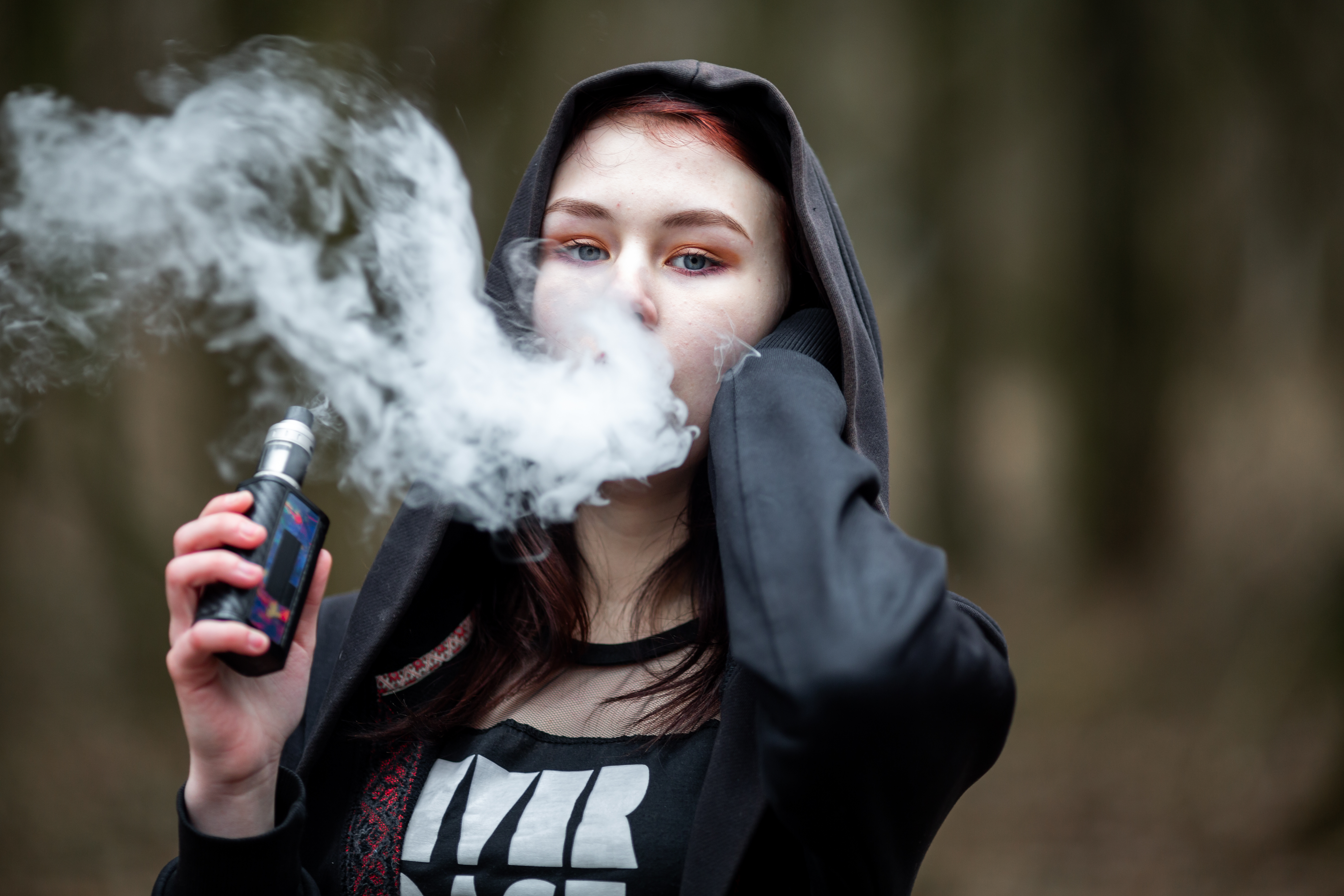 Teenage girl vaping outdoors.