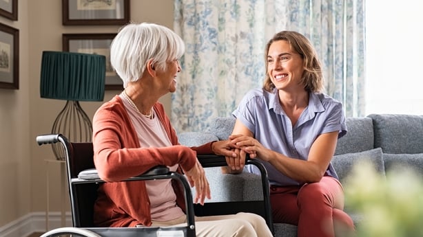 Mature woman comforting senior mom sitting on wheelchair at nursing home