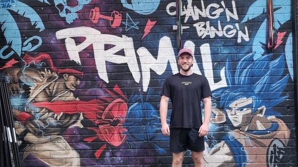 A man stands in front on a painted wall