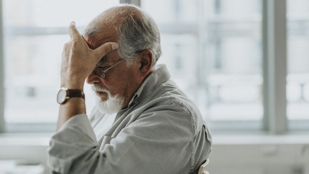 Older man with his head in his hand