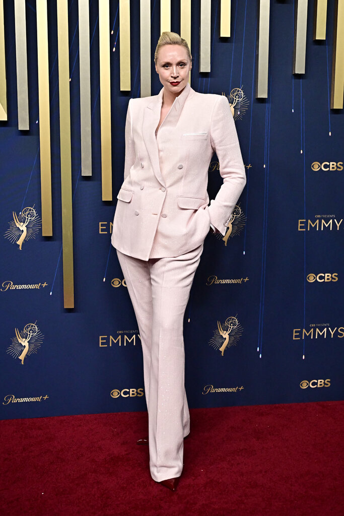 A woman in a pastel suit poses with a hand in her pocket.