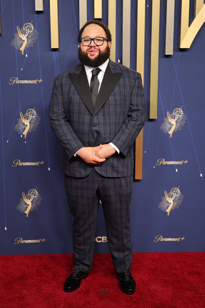 A man wears a dark plaid suit.