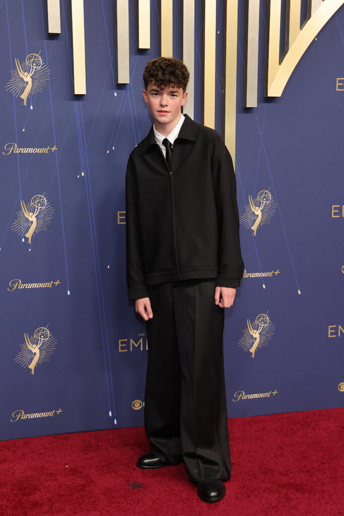 A man wears a black suit with a zip-up jacket.