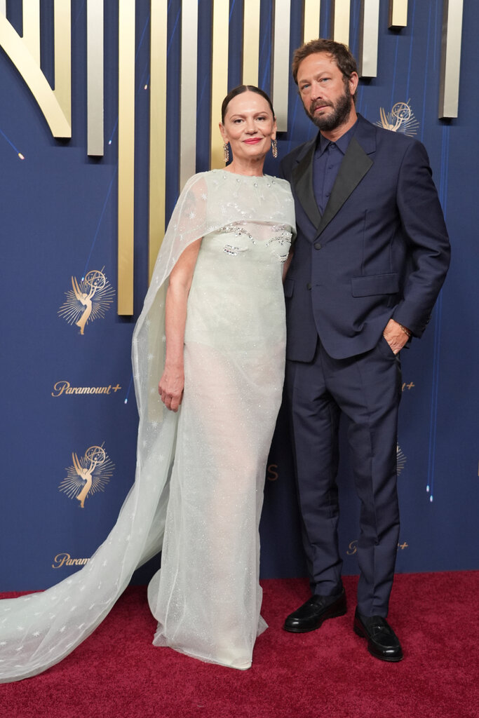 A man in a blue suit (right) poses with a woman in a sheer mint dress and matching capelet.