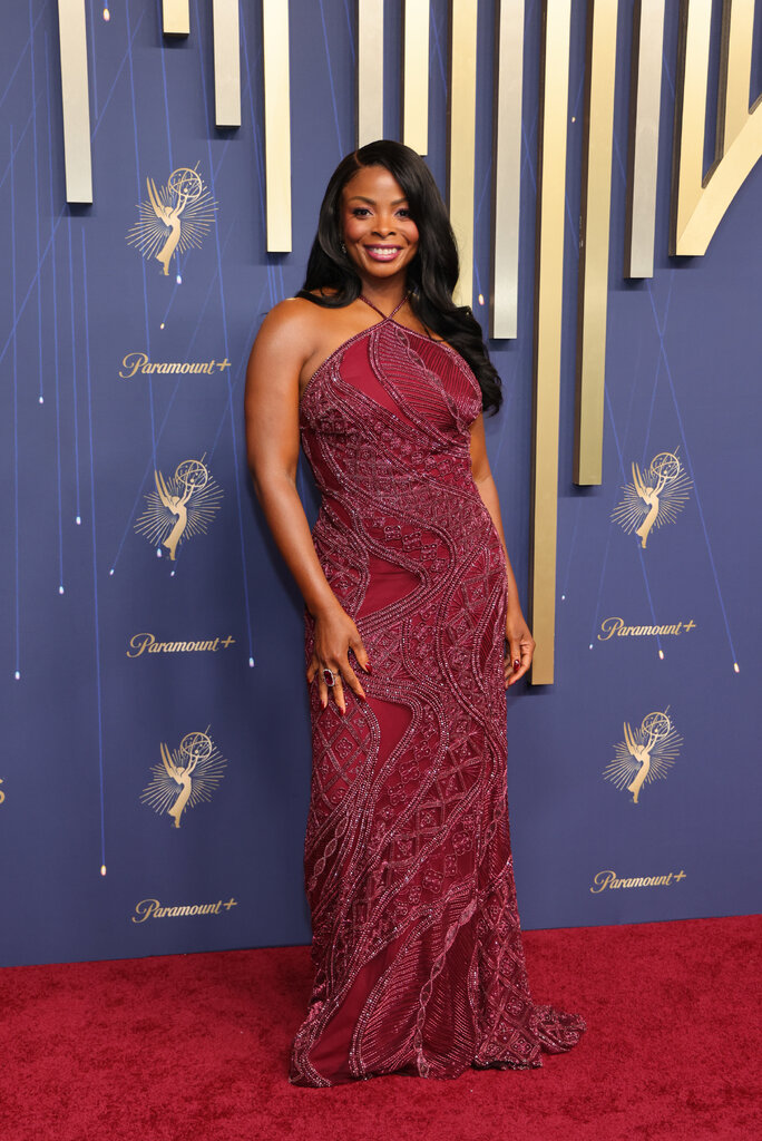 A woman wears a maroon dress with beaded details.