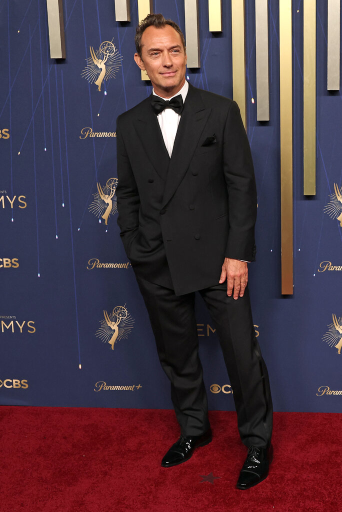 A man wears a black tuxedo.