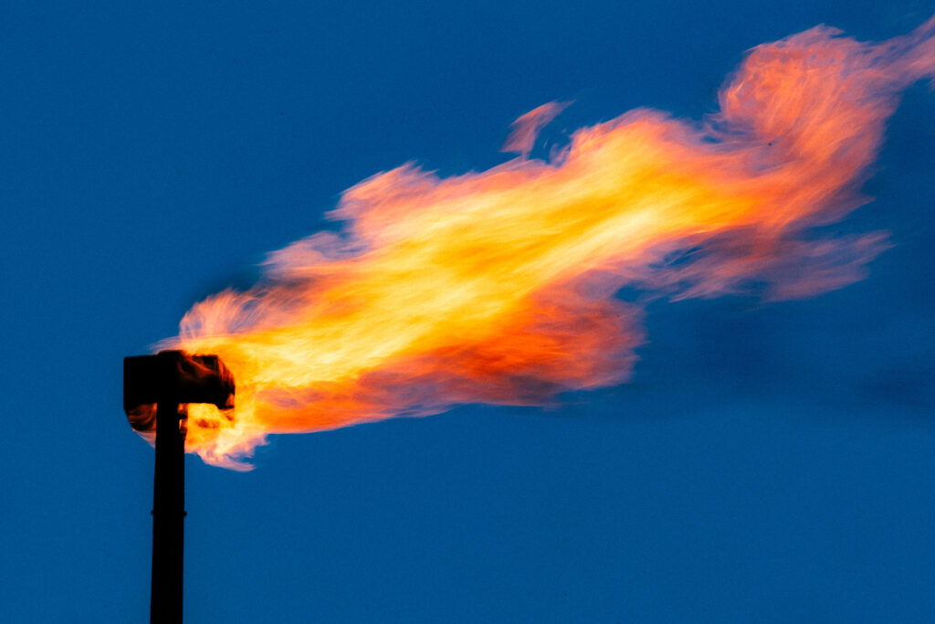 A blackened pipe with a large gout of flame swirling out of the top.