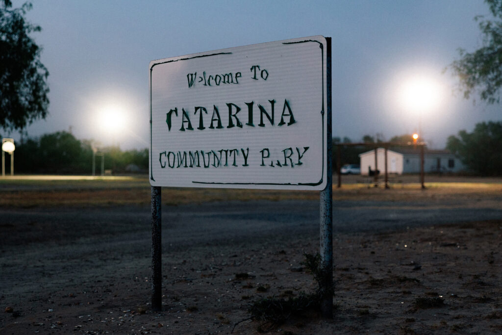 A worn sign for a community park in Catarina at night.