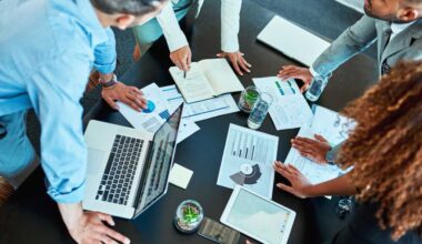 Notebook, hands and group of business people planning solution, discussion or kpi in office meeting. Laptop, sales manager and team together with profit data, budget increase or performance metrics