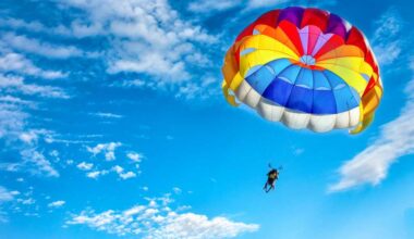 shutterstock 1018105807 rainbow colored parachute against a blue sky and cirrus clouds