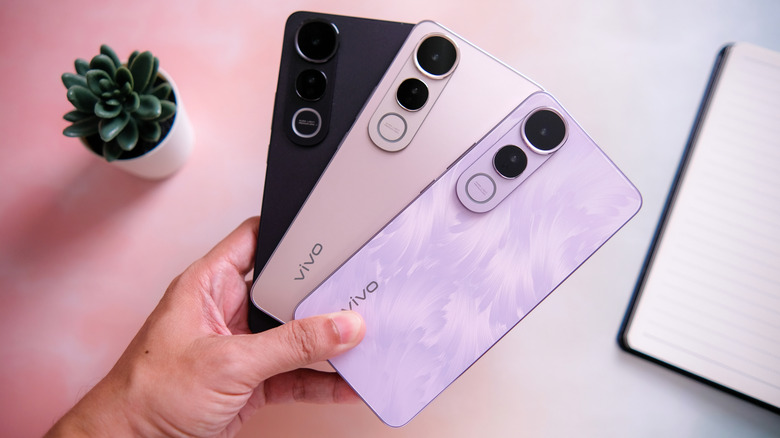 A hand holding Vivo smartphone in black, pink, and purple color