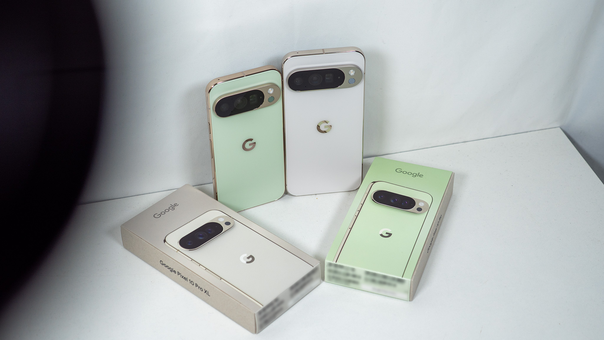 A jade Google Pixel 10 Pro and a white Google Pixel 10 Pro XL with their respective boxes