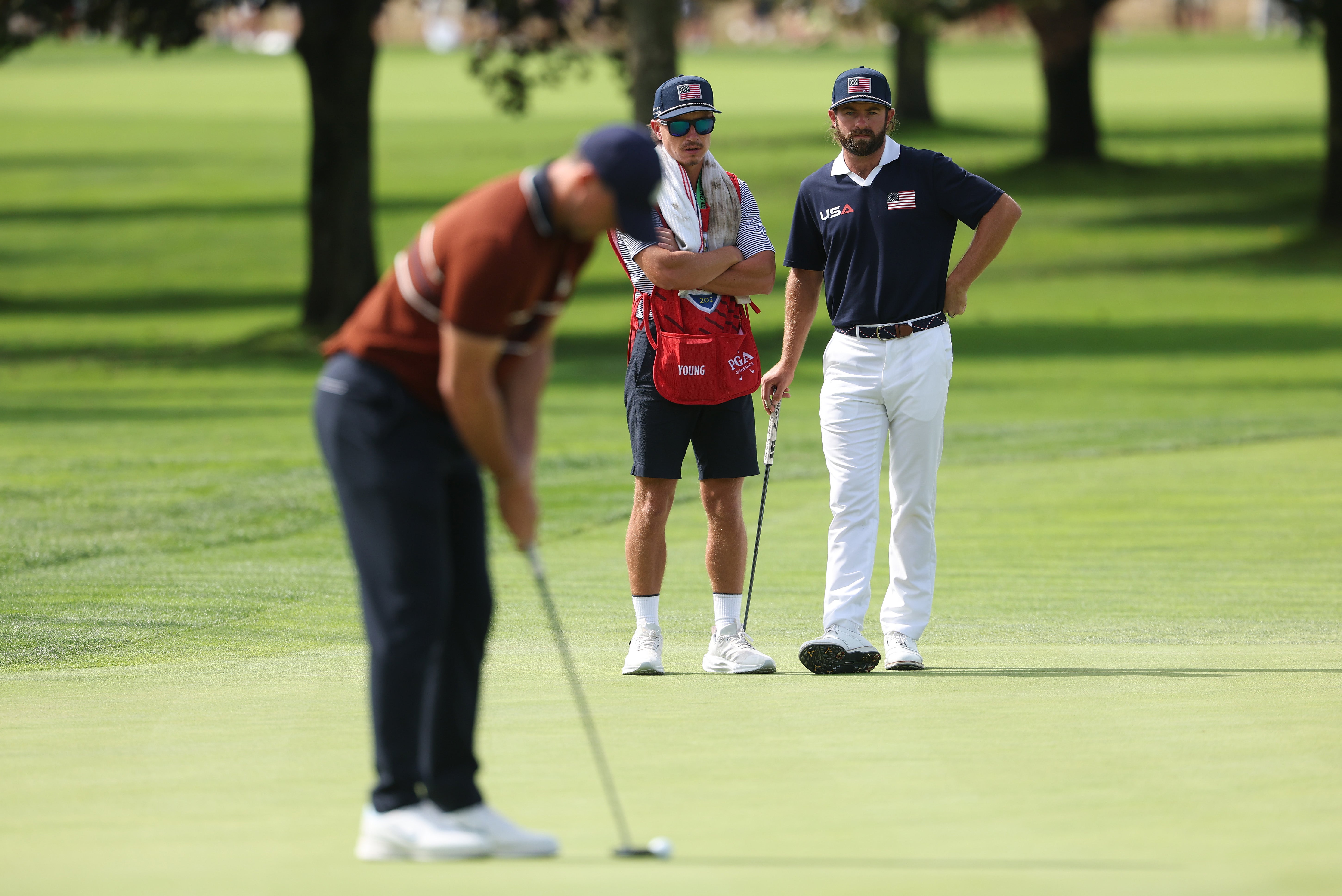 Cameron Young of Team United States watches as Rory McIlroy of Team Europe putts
