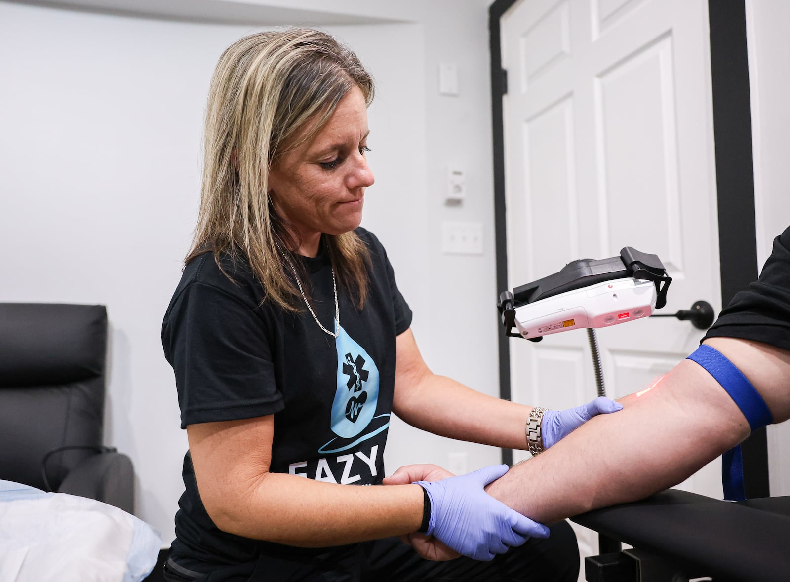 Brittany Kafka demonstrates a vein-finding machine at Eazy iV Hydration and Wellness Clinic in Centerville Tuesday, Sept. 16, 2025. Kafka said the machine uses infrared light to show practitioners vein locations and make IV insertions easier. BRYANT BILLING/STAFF