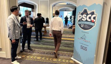 Delegates mingle in the doorway of a large meeting room with a large