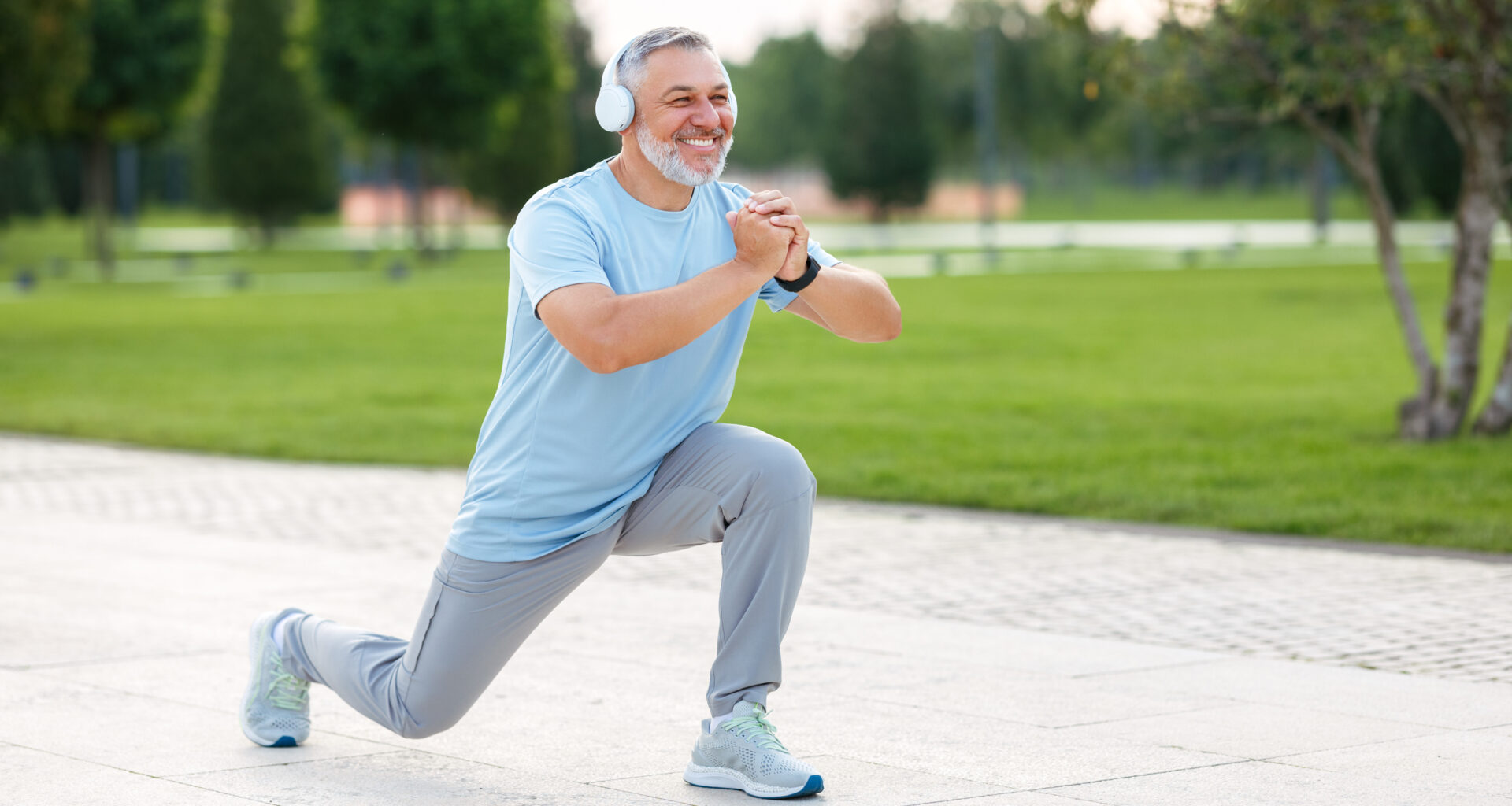 a man in headphones doing a lunge outside