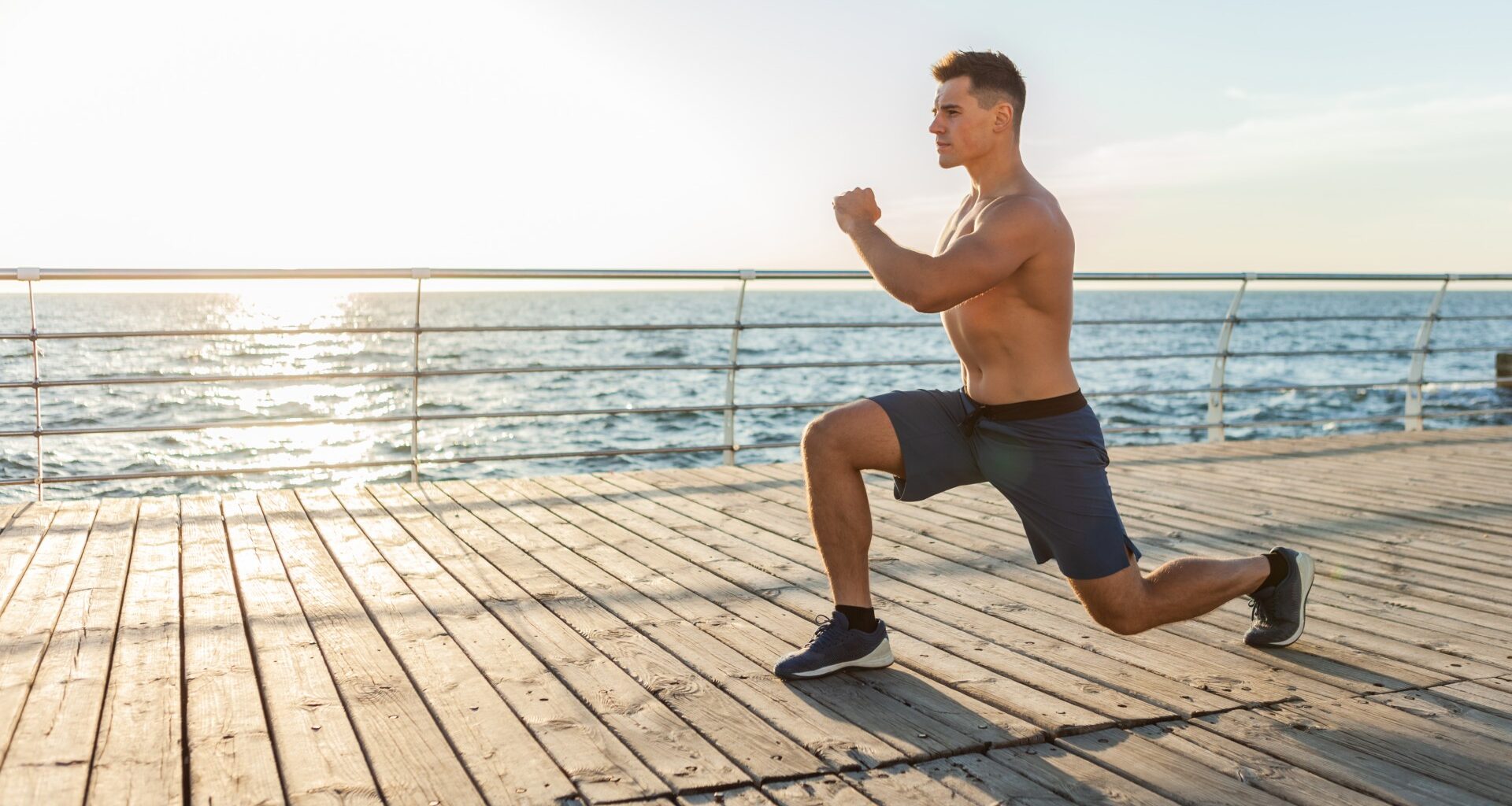 Man performing bodyweight lunges outdoors next to ocean