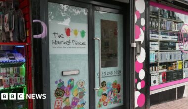 A set of double doors with the name 'The Market Place' emblazoned across them. Some cartoon figures are on the bottom of the door.