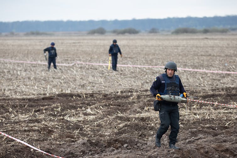 People clearing mines from a field in the Kyiv region of Ukraine.