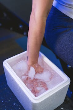 hand immersed in white bucket filled with water and ice